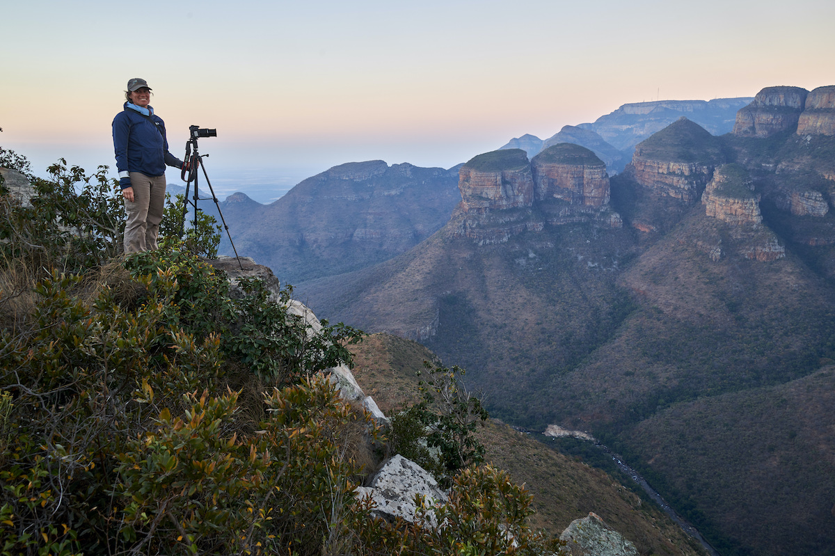 A person stands on a mountain peak, ready to capture the breathtaking view