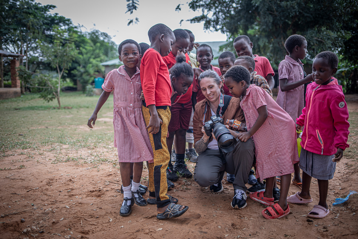 african children surrounding a photographer who has been capturing their images for their NGO