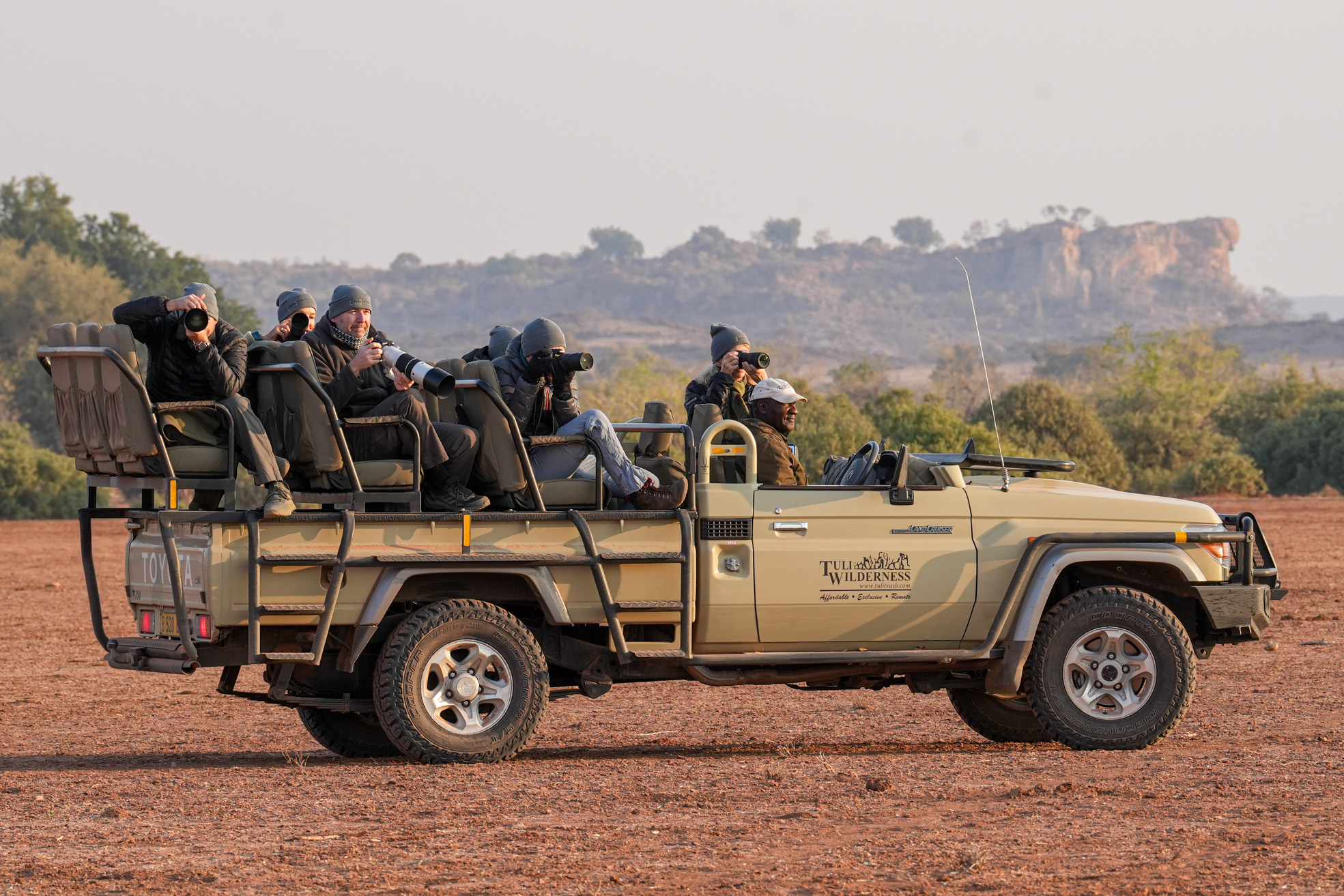 Safari photographers bundled up in a jeep, capturing the scenery with long lenses