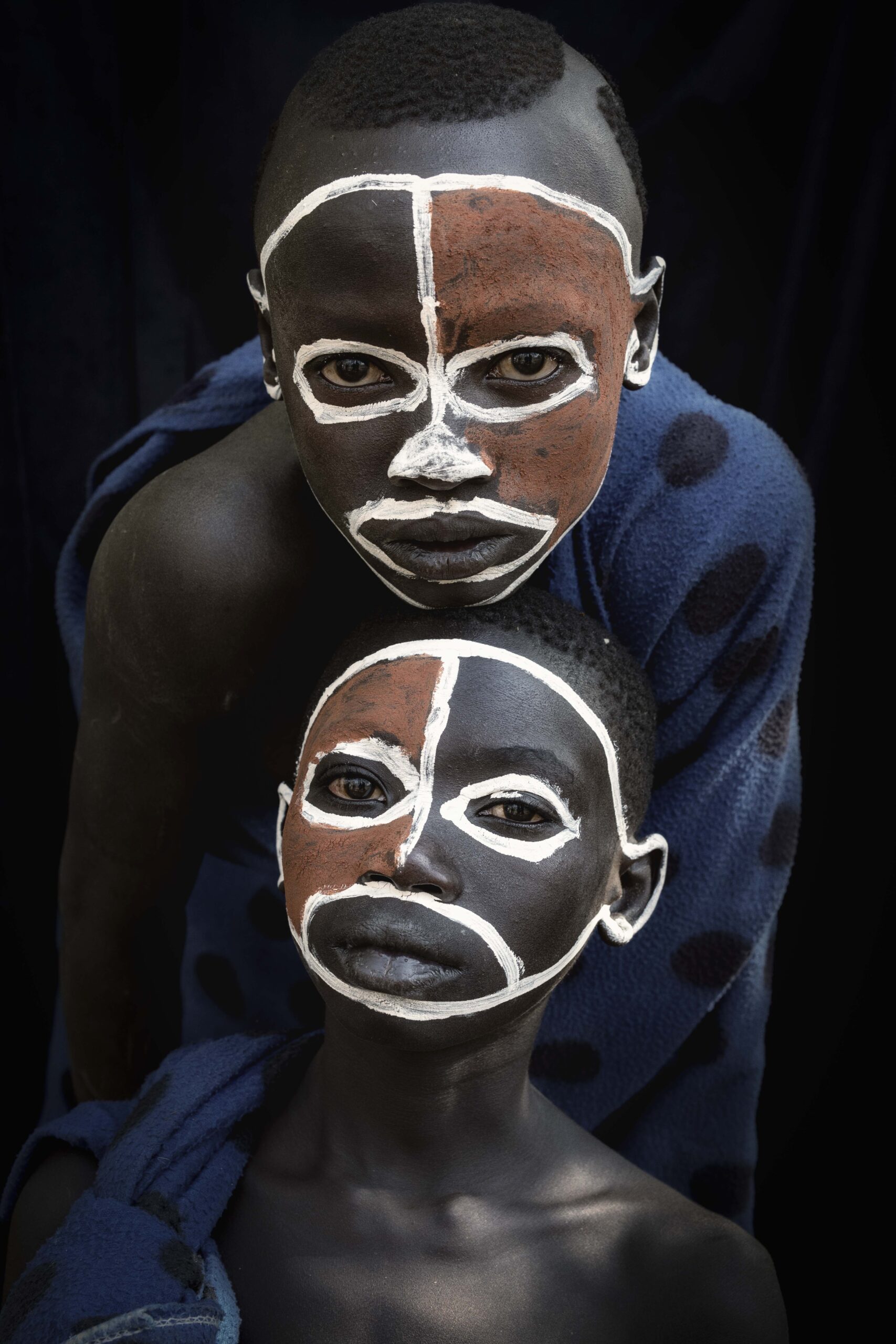 Two children with traditional face paint in white and red posing together