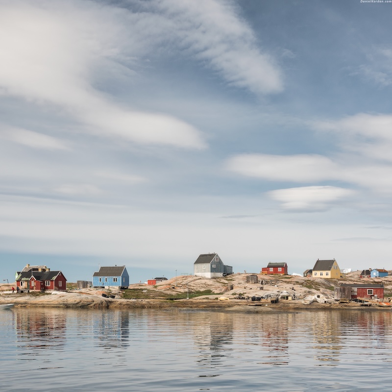 Coastal village with colorful houses on rocky shore under a partly cloudy sky