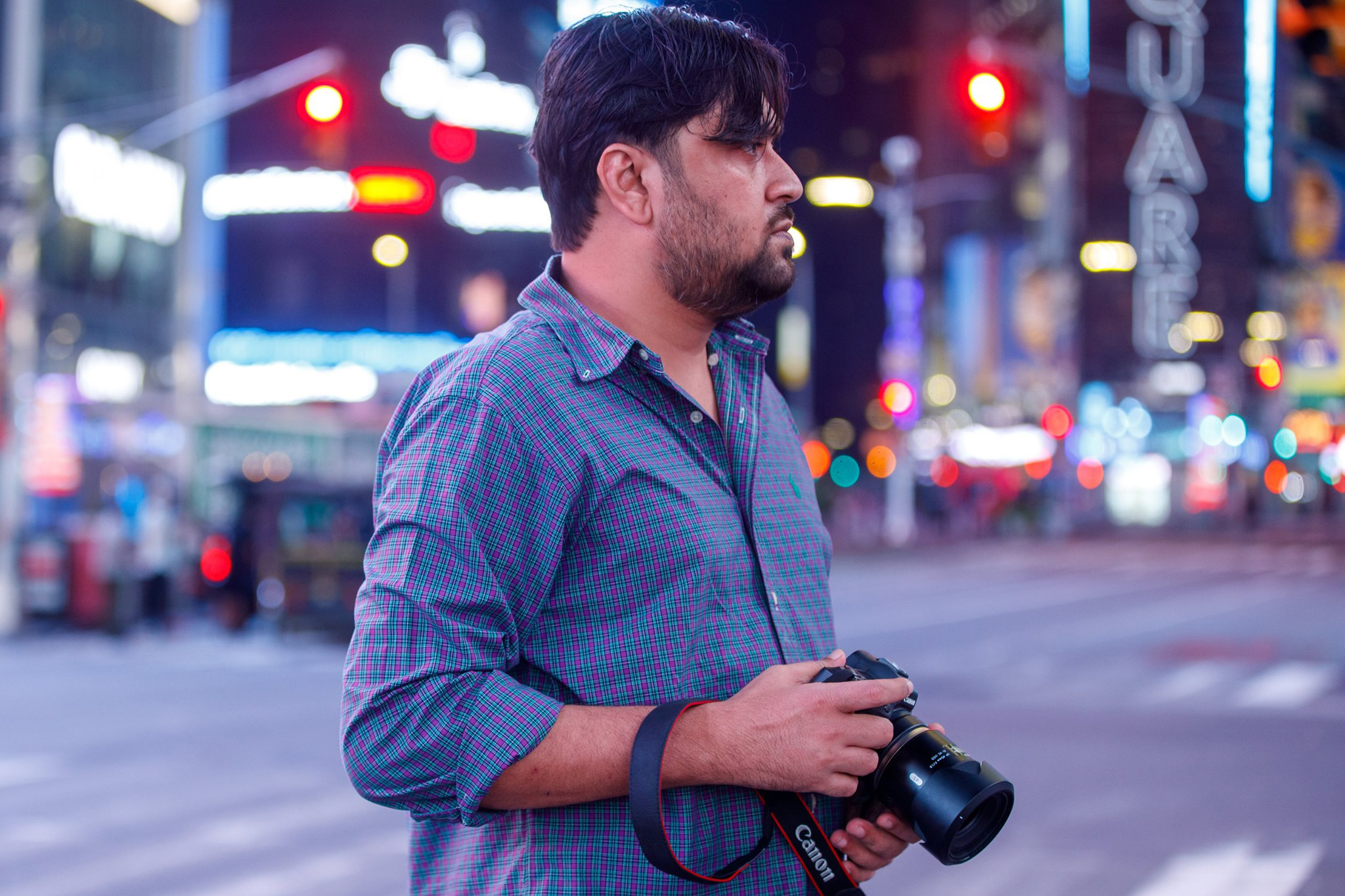 Photographer Tanveer Rohan stands with his Canon camera amid the glowing lights of Times Square at night, featured on the Penda Photo Tours blog.