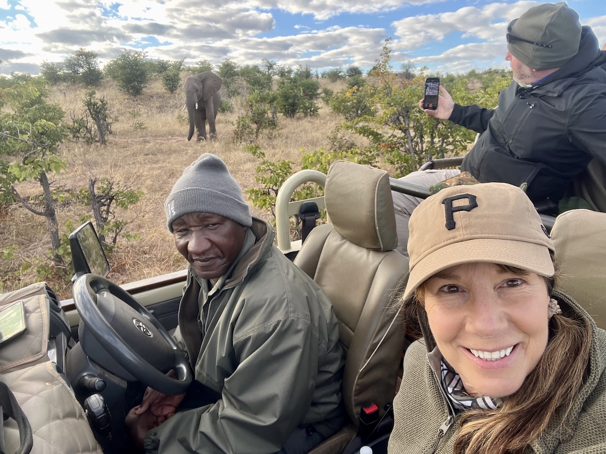 Pandora Maund smiles from a safari vehicle as guests spot an elephant in the distance, captured during the Botswana Photo Safari with Penda Photo Tours.